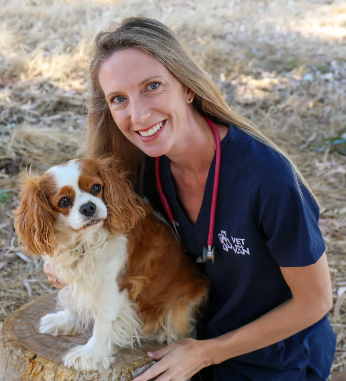 Dr Tania Mitchell, Australian vet, crouching beside her Vet in a Van mobile clinic with a Cavalier King Charles Spaniel